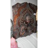 A carved wood panel depicting an Indian Deity.