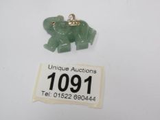 A jade elephant pendant with gold trim and ruby eye.