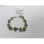 A silver bracelet set green stones.
