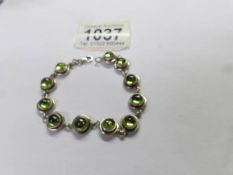 A silver bracelet set green stones.