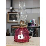 A Victorian cranberry glass finger oil lamp