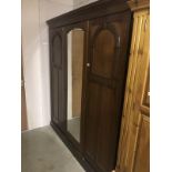 A mahogany triple door wardrobe with central mirror.