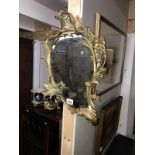 A mirror with ornate gold metal surround with bird feature.