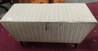 A fabric covered sarcophagus shaped blanket box