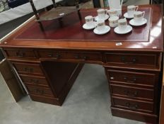 A dark wood stained double pedestal desk with red leather inset