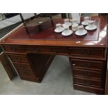 A dark wood stained double pedestal desk with red leather inset