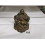 A brass Chinese laughing Buddha seated in a chair with dragon arm rests,