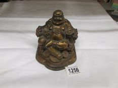 A brass Chinese laughing Buddha seated in a chair with dragon arm rests,