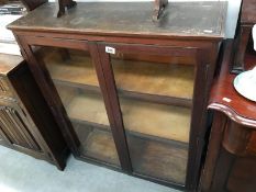 A medium sized plain glass fronted bookcase