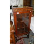 A glass panel fronted carved wood display cabinet