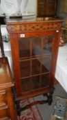A glass panel fronted carved wood display cabinet
