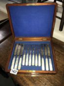 A mahogany cased set of cutlery with mother of pearl handles and engraved blades and forks.