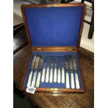 A mahogany cased set of cutlery with mother of pearl handles and engraved blades and forks.