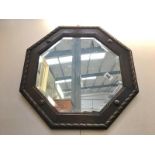 An octagonal bevel edged mirror with carved wood frame