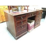 A well used red cloth topped kneehole desk (4 by 1 by 4 drawers)