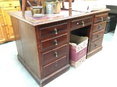 A well used red cloth topped kneehole desk (4 by 1 by 4 drawers)