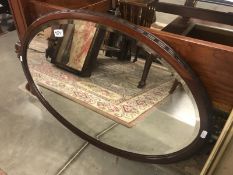 An oval bevel edged mirror in mahogany frame.