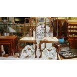 A pair of wood chairs with floral upholstered seats