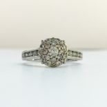 A diamond cluster ring with pave head and channel set shoulders in 18ct white gold,