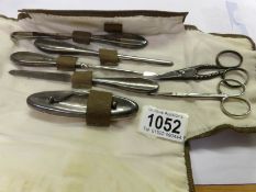A silver handled manicure set and 2 pairs of white metal scissors.