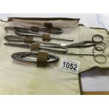 A silver handled manicure set and 2 pairs of white metal scissors.