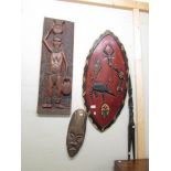 An African carved wood wall plaque, shield, face mask and 2 spears.