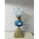 A Victorian oil lamp with blue glass font and original blue swirl shade on a cast iron base.