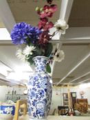 A large blue and white vase complete with silk flowers.