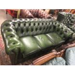 A green leather Chesterfield sofa.