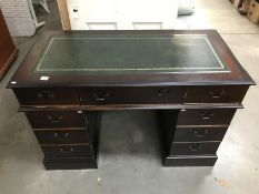 A dark wood desk with green leather insert on top.