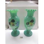 A pair of hand painted green glass vases.