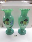 A pair of hand painted green glass vases.