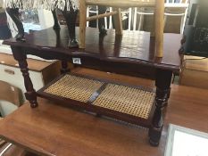 A dark wood stained coffee table with cane shelf.