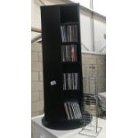 A black revolving CD/DVD stand with a quantity of DVDs and CDs and another chrome CD rack.