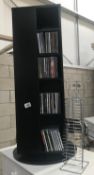 A black revolving CD/DVD stand with a quantity of DVDs and CDs and another chrome CD rack.