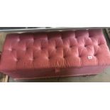 A pink Draylon covered ottoman with deep button top.