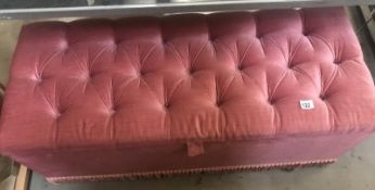 A pink Draylon covered ottoman with deep button top.