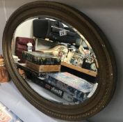 A large oval gilt framed bevel edged mirror.