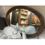 A large oval oak framed bevel edged mirror.