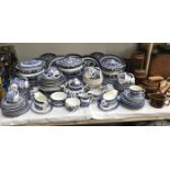 A large quantity of blue willow dinnerware including Hornsea storage jars and teapot.