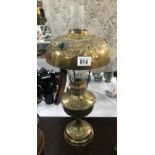 A brass oil lamp with impressed holly decoration and jewels in shade.