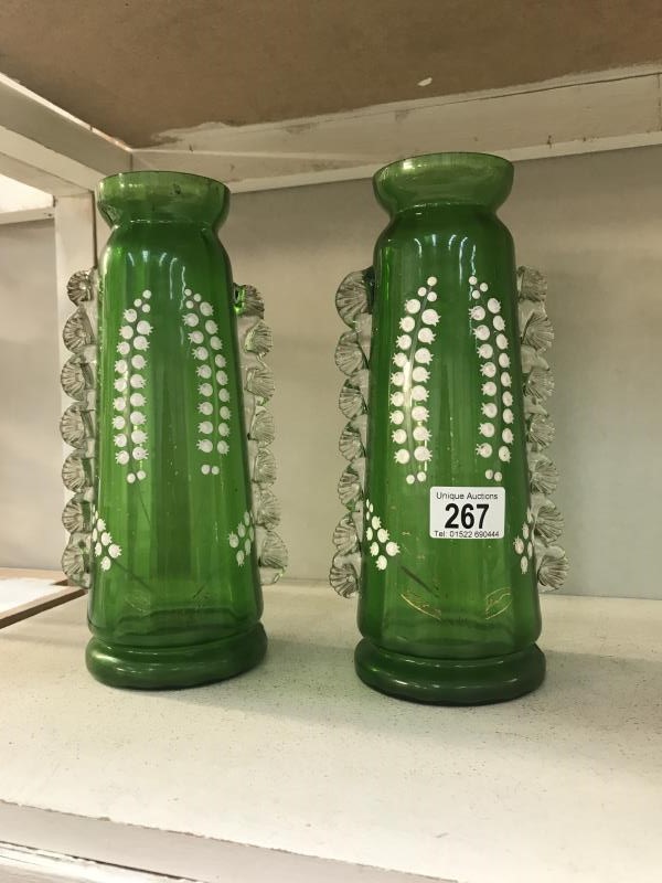 A pair of green glass vases, hand decorated with Lilies of the Valley.