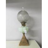 A Victorian oil lamp with pressed green glass font and acid etched shade on a cast iron base.