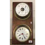 A clock and barometer set on a wooden wall mount.