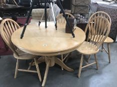 A round lightwood dining table and 4 chairs.