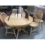 A round lightwood dining table and 4 chairs.