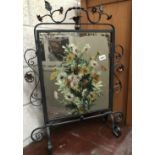 A wrought iron firescreen with hand painted mirror insert.