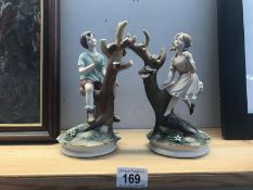 A pair of pottery figures of children climbing trees.