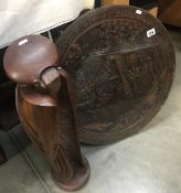 A carved circular wall plaque depicting oriental scene and a modern wooden figure 'The Thinker'.