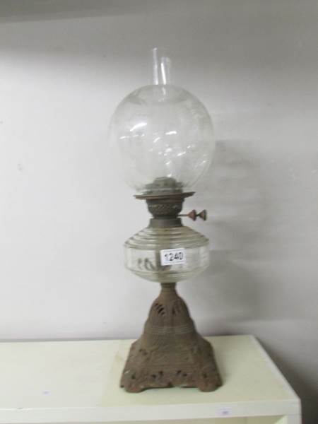 A Victorian oil lamp with clear glass font and floral acid etched shade on a cast iron base.